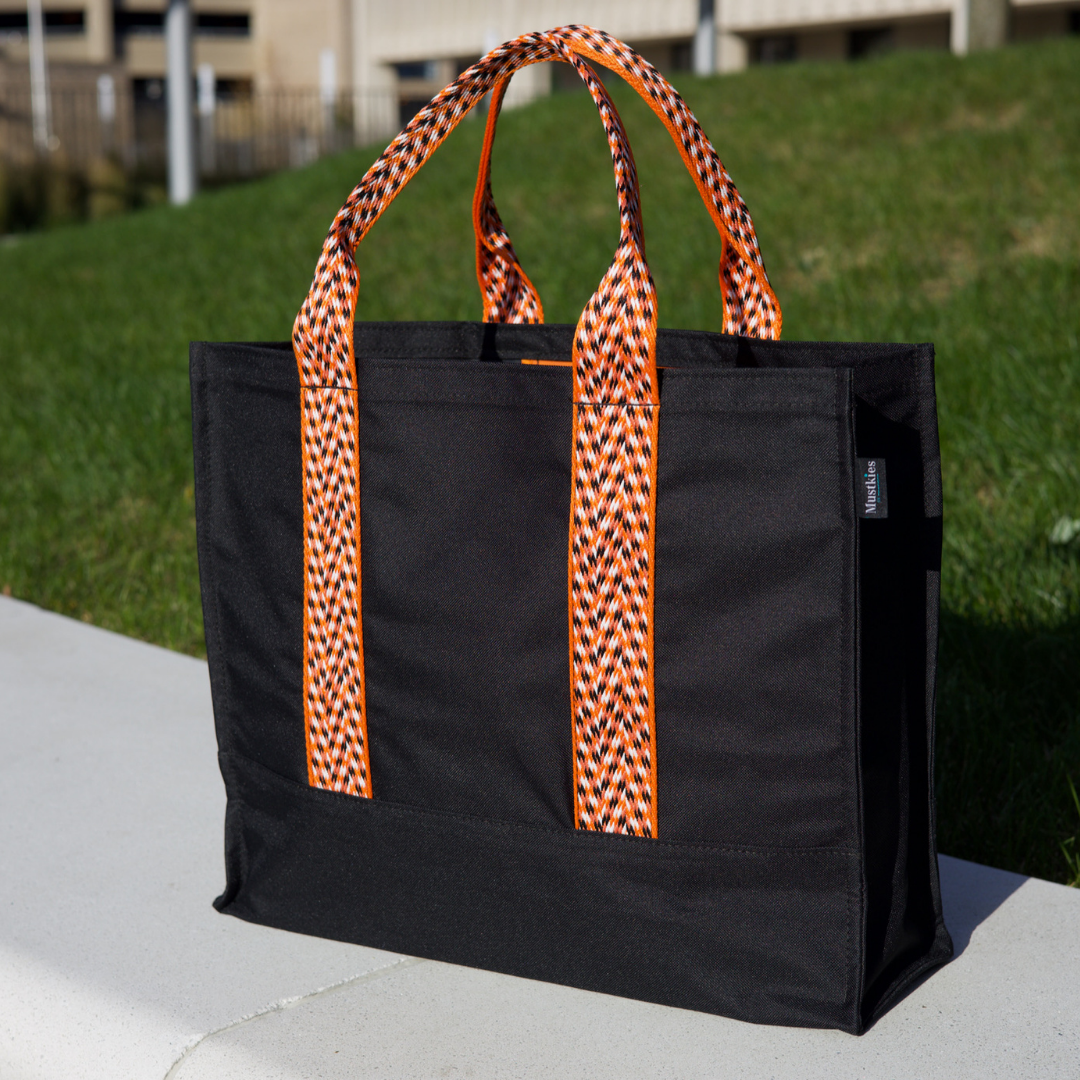 Mustkies CARRIE Tote is your go-to tote. Crafted in a Black waterproof canvas with orange lining and straps. It is a versatile, lightweight everyday bag. Another must-have for running errands, schlepping gear to the kids games, for the beach or even carrying groceries home from the market. White Plains, NY. Westchester County