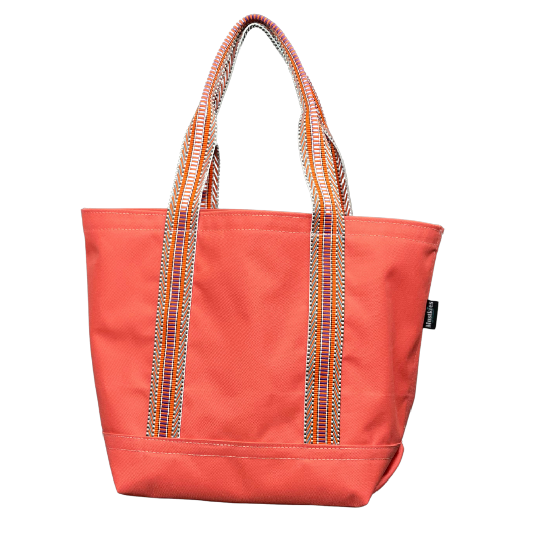 Mustkies Coral Waterproof Canvas Milou Shopper Tote with Orange Multi Webbing. Ultimate Everyday Shopping Tote Bag. Perfect for running errands. Handcrafted with Waterproof Oxford Canvas, which makes it very easy to clean and finished with a Nylon Rainbow Strap. Available in 6 color options. Finished size 10"L x 8"W x 12"T