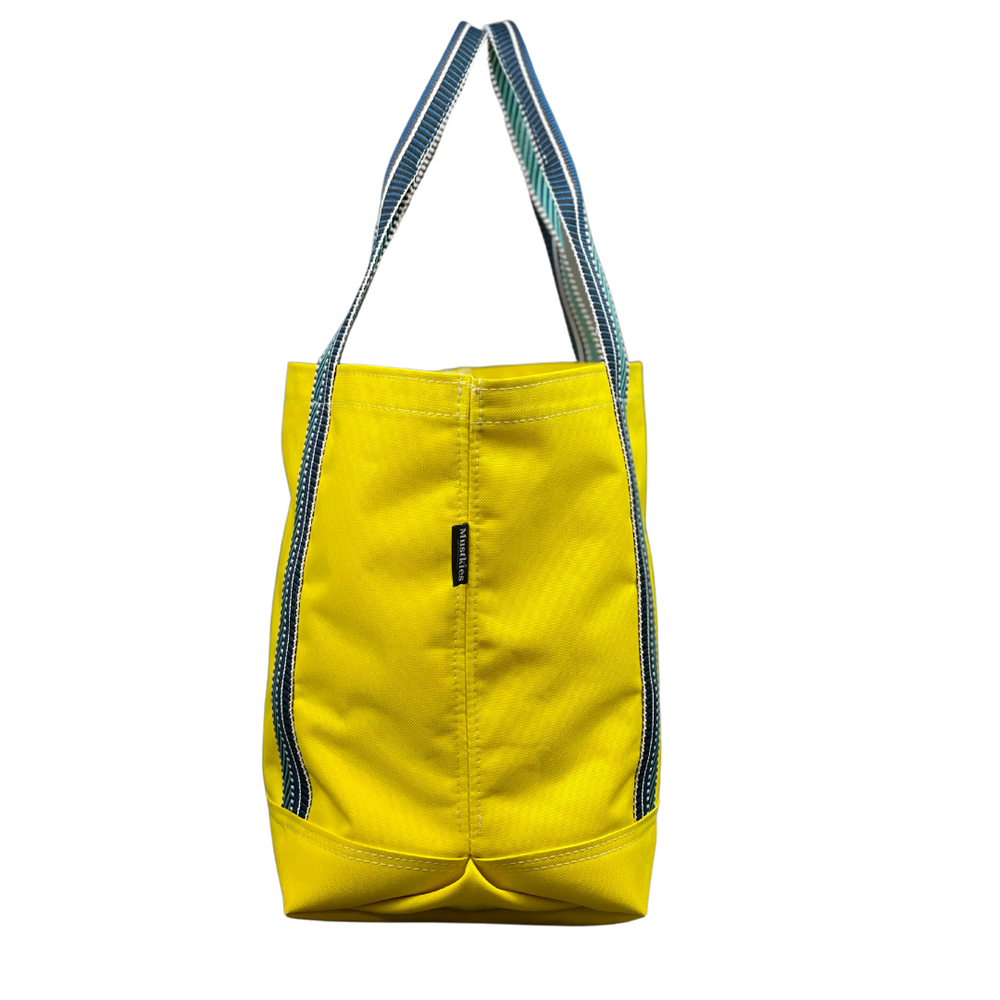 Mustkies Yellow Waterproof Canvas Milou Shopper Tote with Navy/Teal Webbing. Ultimate Everyday Shopping Tote Bag. Perfect for running errands. Handcrafted with Waterproof Oxford Canvas, which makes it very easy to clean and finished with a Nylon Rainbow Strap. Available in 6 color options. Finished size 10"L x 8"W x 12"T