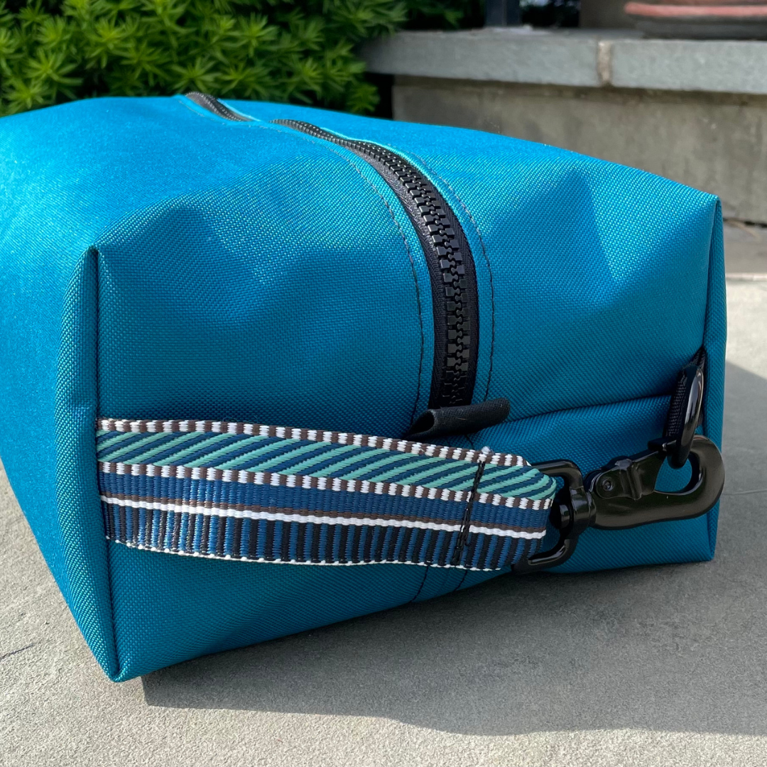 Mustkies LIZZIE Teal With Black strap Unisex Sports GOLF Shoe Bags Color Sample. Designed specifically for golfers. Can fit multiple shoes depending on the shoe size and up to a men's size 13. Signature buckle added to the original GERI shoe bag so you can click it on your golf bag. Great for multiple sports use or even can be used a organizer in your suitcase to keep your shoes separate from your other belongings. Handcrafted in White Plains NY, Westchester County.