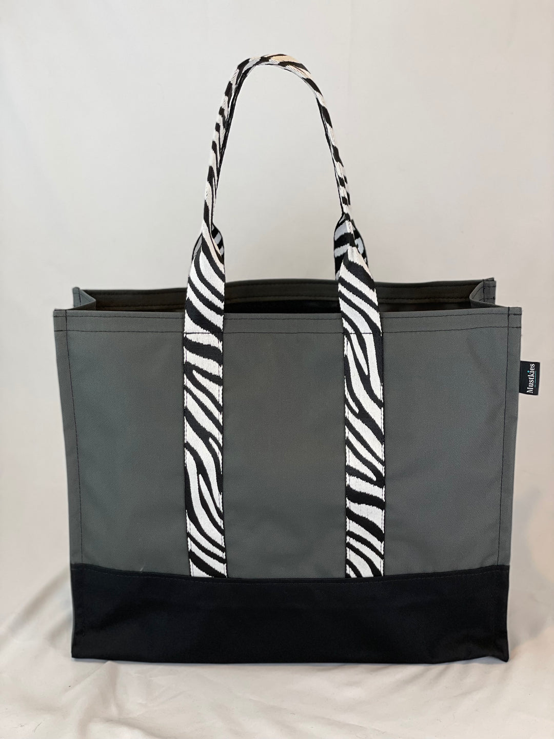 Mustkies CARRIE Tote is your go-to tote. Crafted in a Gray waterproof canvas with black lining and Zebra pattern straps. It is a versatile, lightweight everyday bag. Another must-have for running errands, schlepping gear to the kids games, for the beach or even carrying groceries home from the market. White Plains, NY. Westchester County